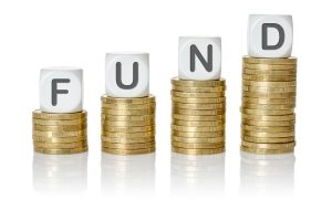 Stacks of gold coins with letter cubes spelling FUND, increasing in height from left to right.