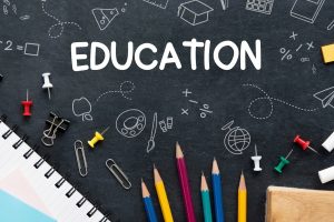 Chalkboard with the word EDUCATION and colorful pencils, paper clips, and school doodles around it.
