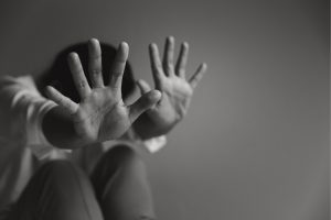 Child reaching out with hands toward the camera, fingers spread, in black and white.