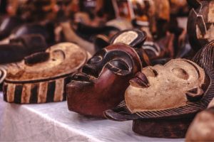 Assorted carved wooden masks displayed on a market stall table.