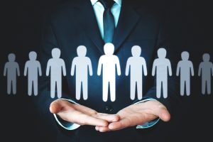 Businessman cupping a row of white human icons, symbolizing protection or management of employees.
