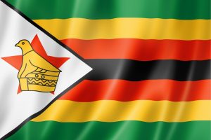 Flag of Zimbabwe with a white left triangle containing the Zimbabwe Bird emblem on a pedestal and red star, set against green, gold, red, and black horizontal stripes above and below the triangle.
