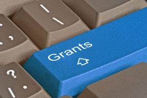 Blue keyboard key labeled 'Grants' with a small white graduation cap icon.