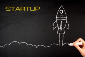 Chalkboard illustration of a rocket ready to launch with the word STARTUP in yellow, drawn by hand with chalk.