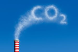 Factory smokestack with red-and-white stripes releasing a cloud shaped like 'CO2' into a clear blue sky, illustrating emissions.